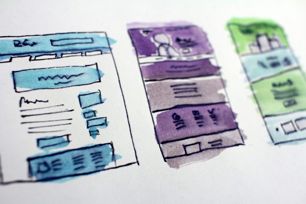 Hand-drawn website wireframes with watercolor highlights.